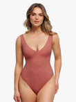 Woman wearing a rose-colored all-in-one shaping bodysuit with a deep V-neck.