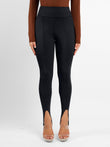 Black high-rise stirrup shapewear leggings with arc seams.