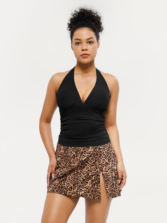 Black halter tankini top with ruched sides paired with a leopard print skirted bottom featuring a high slit.