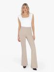 Woman in white padded shoulder slimming bodysuit and beige flare-leg pants.