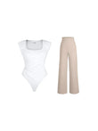 White square-neck, padded shoulder bodysuit with ruched waist paired with beige wide-leg pants.